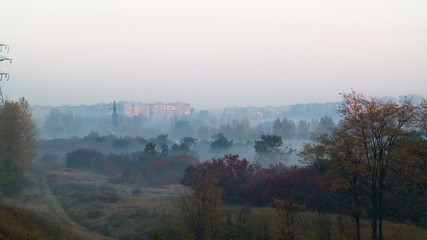 Misty sunrise in colourful autumn forest near the city