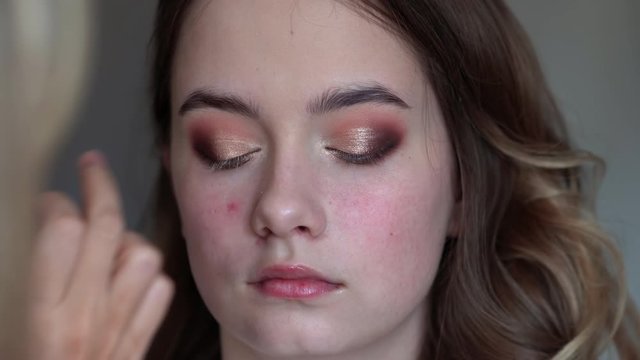 Makeup artist paints eyelids on a model girl.