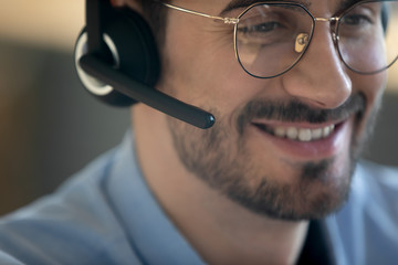 Close up head shot smiling man wearing headset with microphone, friendly call center worker...
