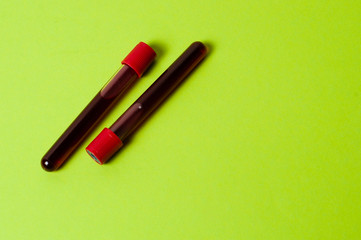 Two test tubes with blood isolate on green background. Concept medicine, the fight against viruses and bacteria, diseases