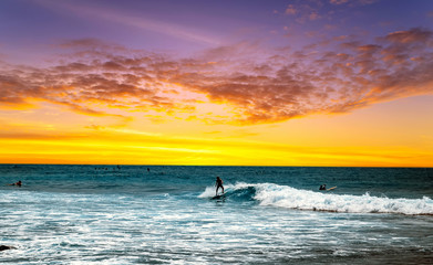 Fototapeta premium Silhouette Surfer Blue Ocean Wave Sunrise surfboard on a beach at sunset.
