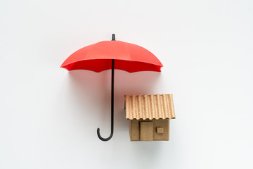 House insurance with a house protected under a red umbrella as a symbol of residential security...