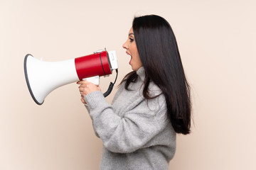 Naklejka premium Young Colombian girl over isolated background shouting through a megaphone