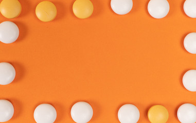Yellow and orange tablets lie on an orange background