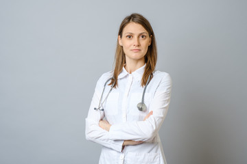 Smiling female doctor in lab coat with arms crossed