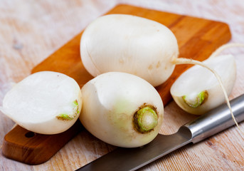 Ripe white radish and knife on wooden cutting board