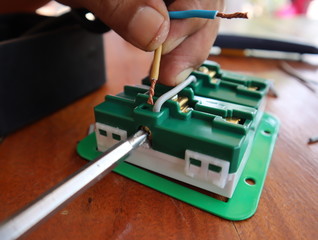 Electricians tighten the screws to connect the electrical plug.