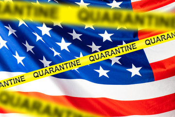 An American flag behind a restraining tape with the words Quarantine. Quarantine due to coronavirus in the United States. Ban flights to America. Self-isolation regime in the United States.