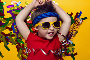 child a boy in a red t shirt and sunglasses is lying on yellow paper