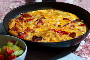 Rustic omelet with potatoes, tomatoes and sausage in a pan