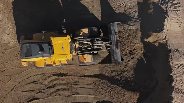 Overhead aerial view loading bulldozer in open air quarry.
