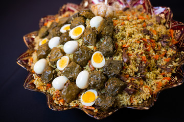 Traditional georgian dolma in grape leaves on black table with female hand