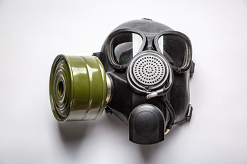 black gas mask with a filter lies on a table close-up on a white background. Horizontal orientation.