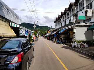 Fototapeta premium Car street road electricity cable mast houses village pai middle centre shops walking north chiang mai mountain green