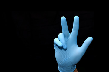 hand in a medical glove shows a symbol of victory.
