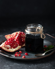 pomegranate sauce in a glass jar on a dark background, place for text