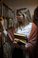 Young blonde girl with glasses in the library. Photographed close-up.