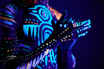 cropped photo of young male hands, UV body art glows. fantastic luminescent paint in neon light