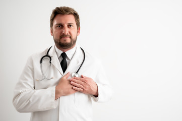 Male doctor with stethoscope in medical uniform holds her hands on her chest near her heart