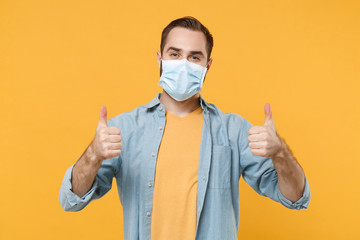 Young man in sterile face mask posing isolated on yellow wall background studio portrait. Epidemic...