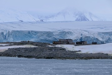 Stonington Island east base with glacier in background and dark ocean, Antarctica