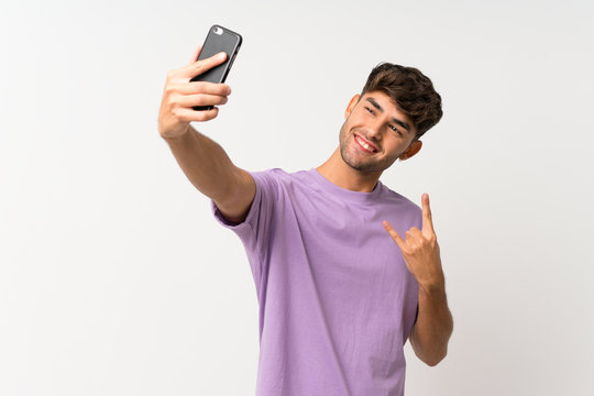 Young handsome man over isolated white background making a selfie