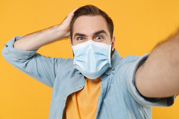 Close up of puzzled man in sterile face mask isolated on yellow background. Epidemic pandemic...