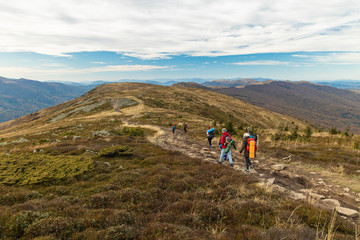 Obraz premium group of people back to camera walking on mountain ridge highland windy scenery environment moody nature surrounding of autumn weather