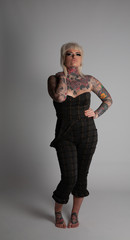 Tattooed Model. Young blonde woman with many tattoos wearing a body siut. Posing on a white background.