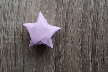 Purple origami star on wooden