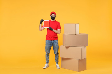 Delivery man employee in red cap blank t-shirt uniform face mask glove hold empty cardboard box isolated on yellow background studio Service quarantine pandemic coronavirus flu virus 2019-ncov concept