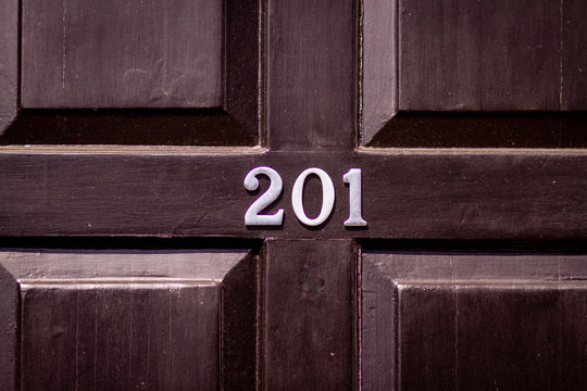 House number 201 on a black wooden front door with panels in London