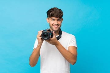 Obraz premium Young handsome man over isolated blue background with a professional camera