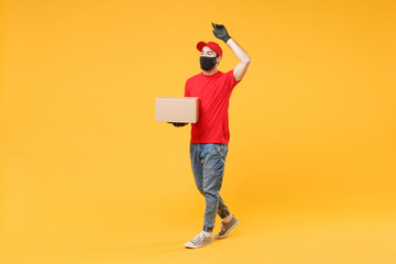 Delivery man employee in red cap blank t-shirt uniform face mask glove hold empty cardboard box isolated on yellow background studio Service quarantine pandemic coronavirus flu virus 2019-ncov concept