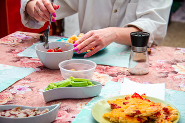 Obraz na płótnie Canvas Breakfast. Various colorful breakfast dishes on a plate with cutlery in the hands of a woman. Omelet, cucumbers, tomatoes, bacon.