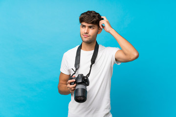 Young handsome man over isolated blue background with a professional camera and thinking