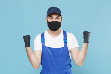 Delivery man in cap t-shirt coveralls uniform sterile face mask gloves isolated on blue background studio. Guy employee courier Service quarantine pandemic coronavirus virus covid-19 2019-ncov concept
