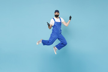Plakat Fun jumping delivery man in cap t-shirt uniform sterile face mask glove isolated on blue background studio Guy employee courier Service quarantine pandemic coronavirus virus covid-19 2019-ncov concept