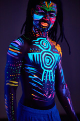 young handsome african man with fluorescent prints on body glowing on neon lights, colorful prints, body art concept