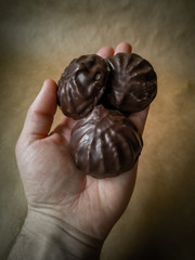 White marshmallows in chocolate on parchment paper. Chocolate marshmallows on your hand.