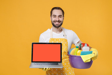 Smiling man househusband in rubber gloves hold basin detergent bottles washing cleansers doing...