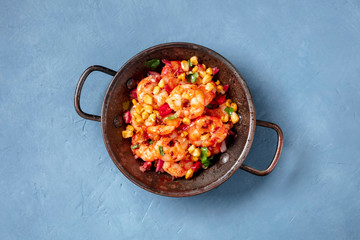Spicy shrimps with corn in a copper pan, shot from the top