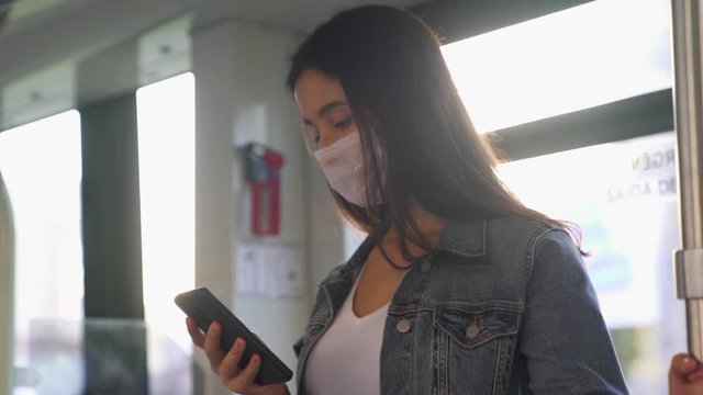 Young woman in protective medical face mask on a train subway car, pandemic coronavirus concept
