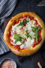 Pizza Margherita on black stone background, top view.