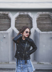 stylish girl in sunglasses and leather jacket posing in the city