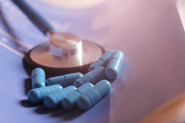 Blue capsules and a stethoscope so close, toned