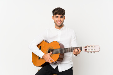 Young handsome man with guitar over isolated white background smiling a lot