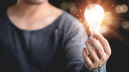 Hand of man holding illuminated light bulb, idea, innovation and inspiration concept.concept creativity with bulbs that shine glitter.