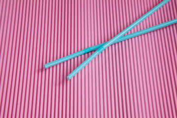 Blue two drinking straws on a pink background, without a plastic Cup.