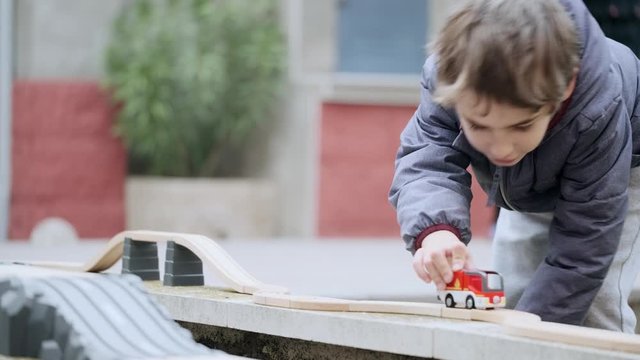 Video of little boy playing on the terrace at home with an automobile and the circuit toy.